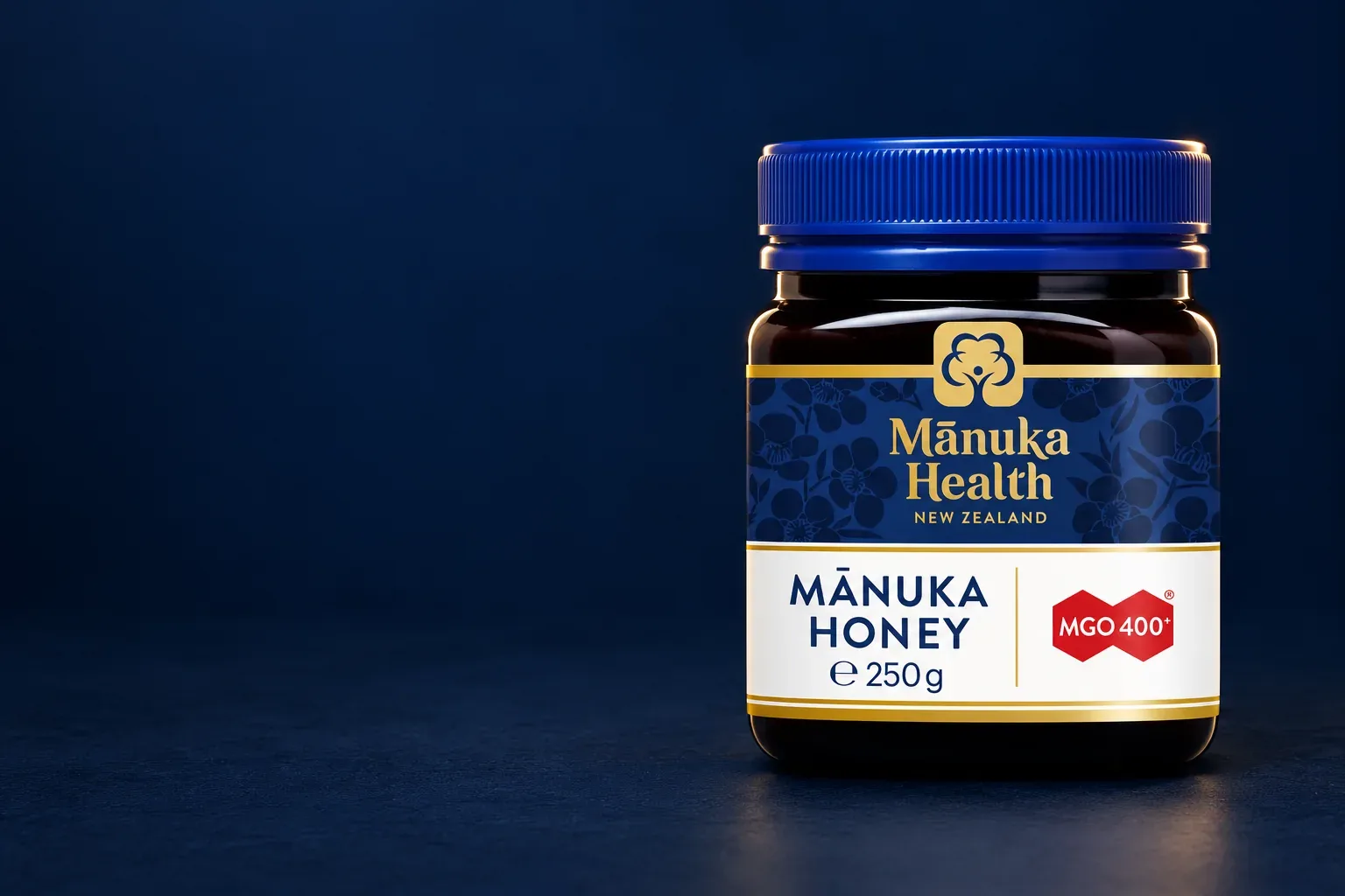 Pôvodný med Manuka Health MGO 400+ 250 g s modrým viečkom na tmavomodrom pozadí