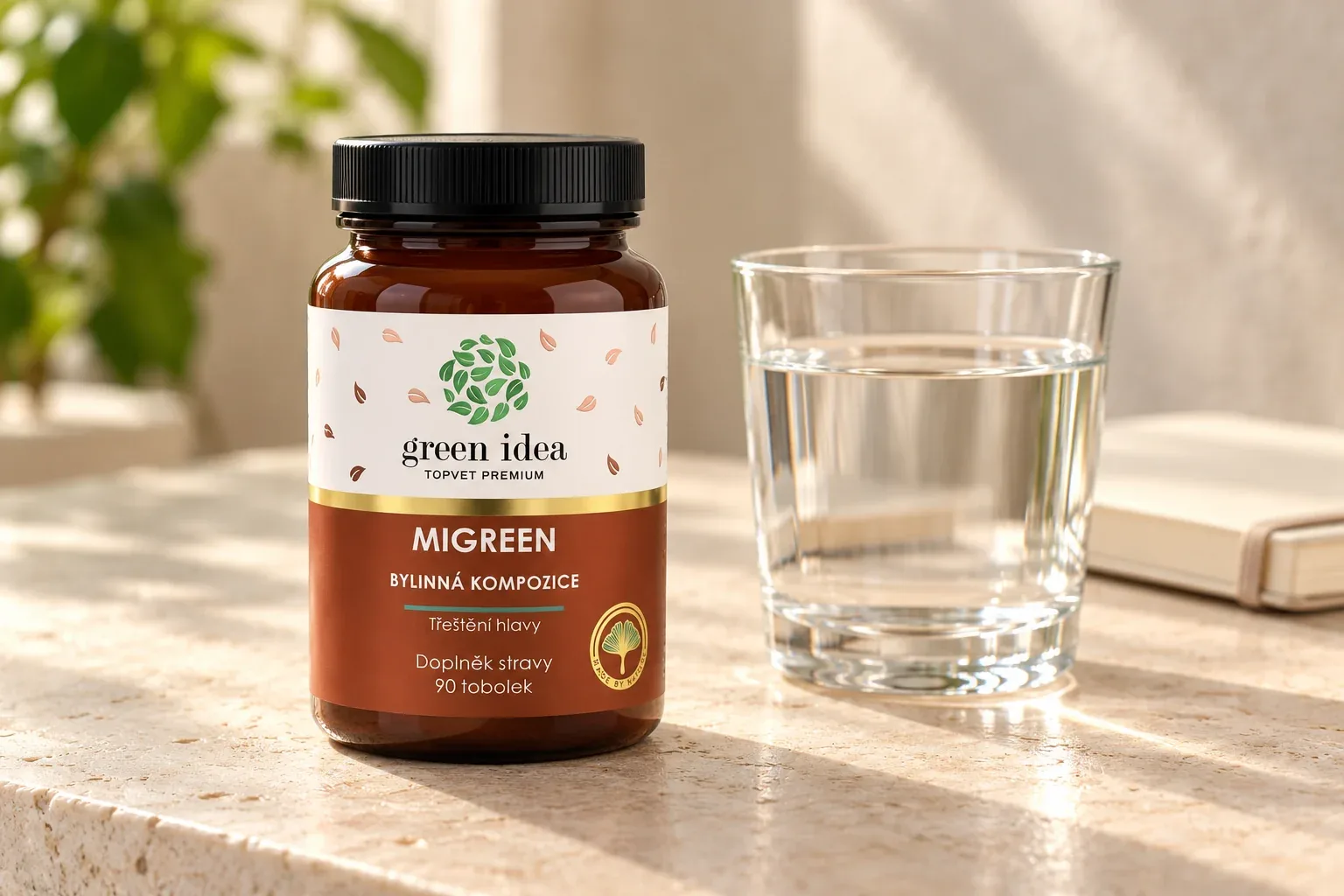Migreen Green idea na svetlom stole vedľa pohára vody