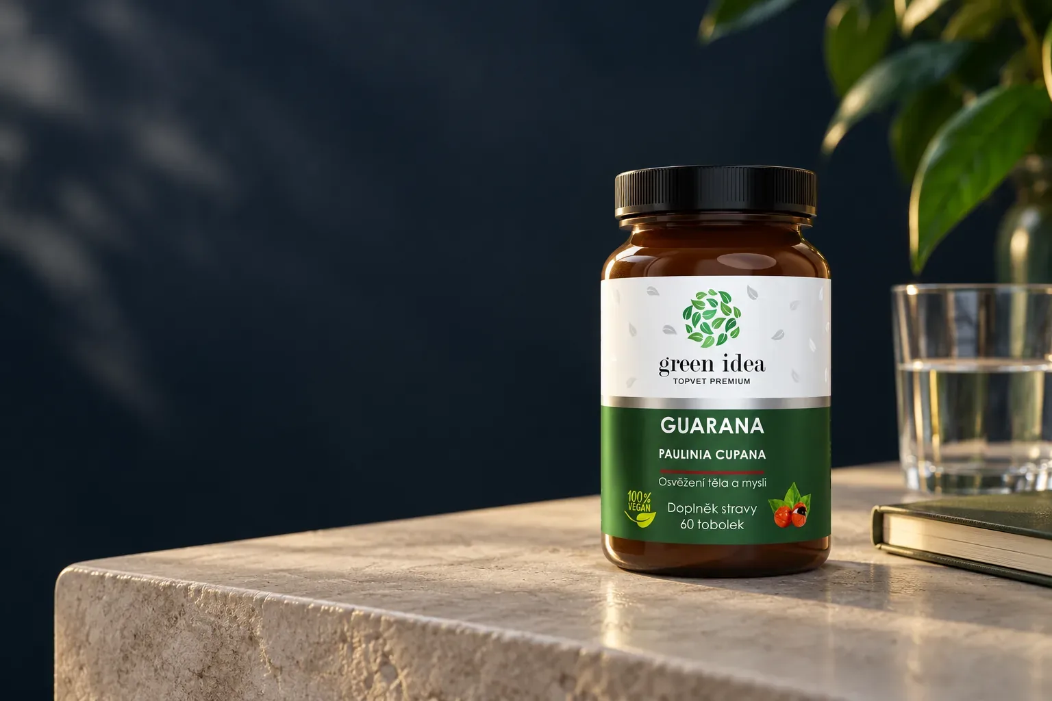 Green idea Guarana v pôvodnom balení vedľa pohára vody a zatvoreného zápisníka